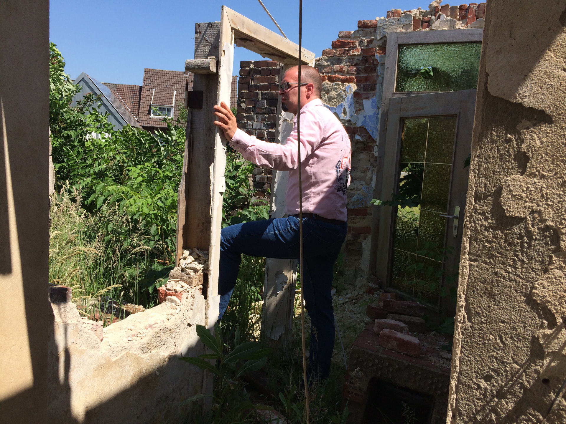 Robin stands in the doorway of a half-demolished house, looking out through the empty frame