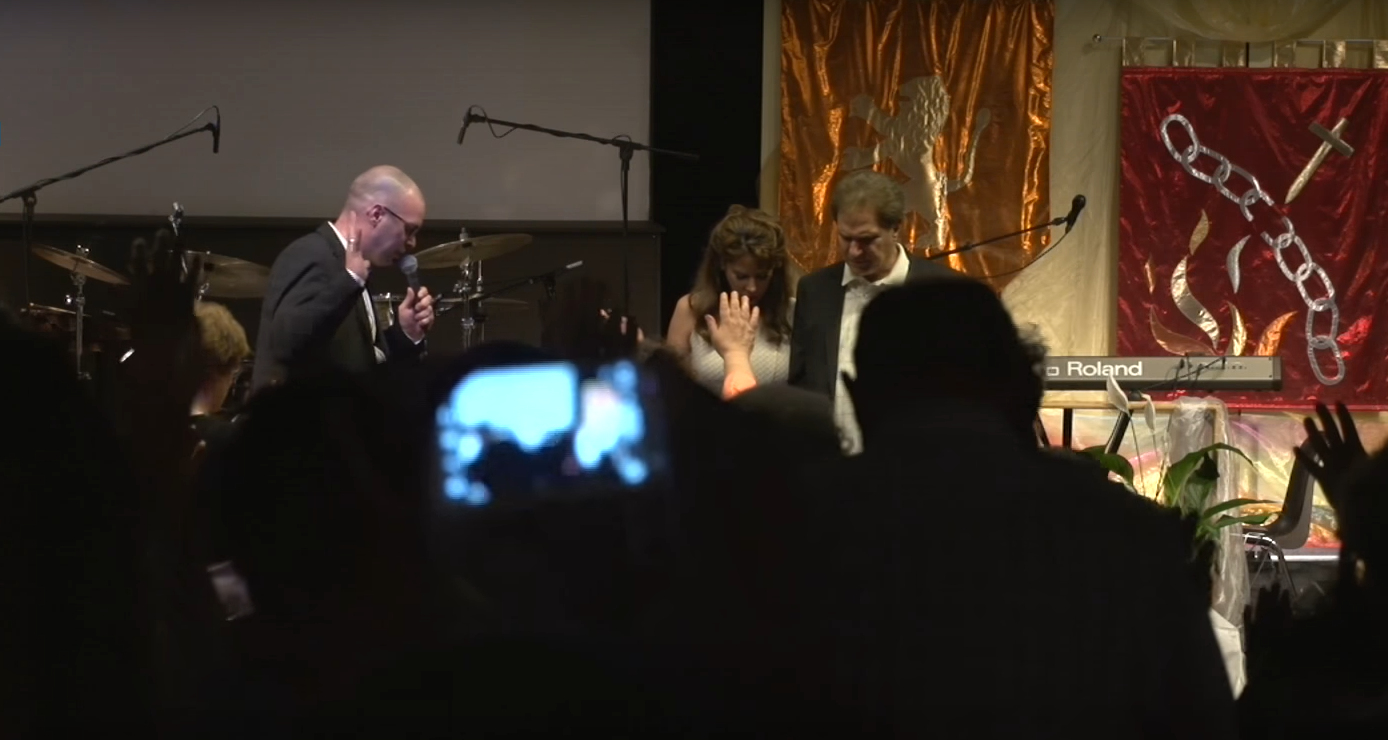 Praying together on stage at LoveUnlimited Ministries